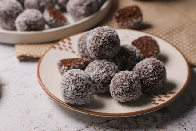 A few coconut balls on a plate, with one of them cut in half
